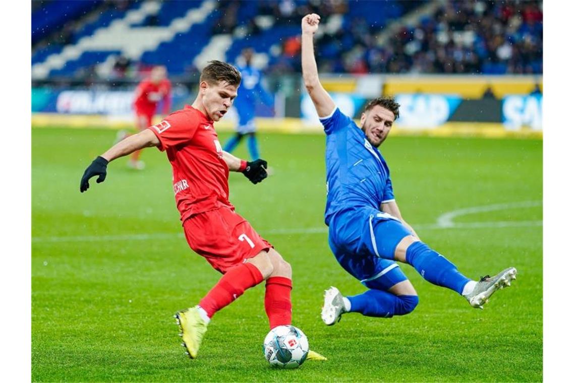 Augsburgs Florian Niederlechner und Hoffenheims Ermin Bicakcic (l-r.) im Zweikampf um den Ball. Foto: Uwe Anspach/dpa