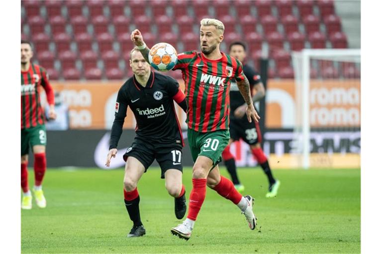 Augsburgs Niklas Dorsch (v) versucht, den Ball gegen Eintrachts Kapitän Sebastian Rode zu behaupten. Foto: Matthias Balk/dpa