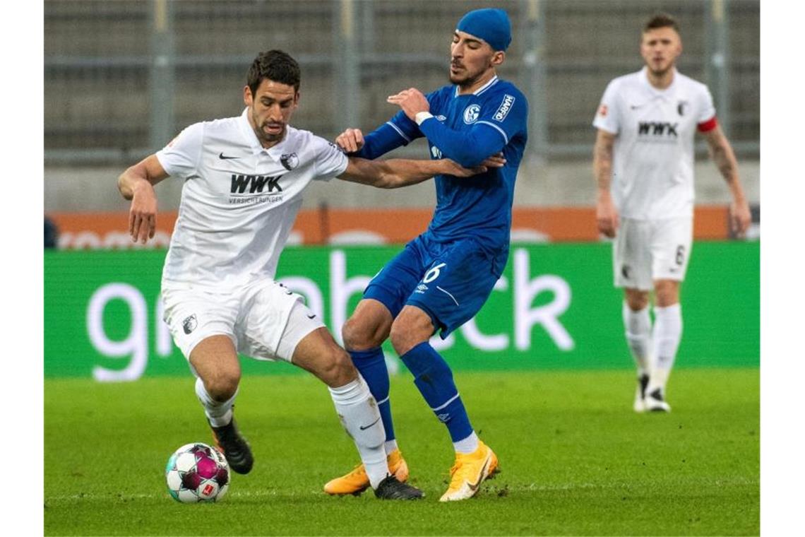 Schock für Schalke: Uth-Verletzung und spätes Remis Augsburgs Rani Khedira (l) im Zweikampf mit Schalkes Nassim Boujellab. Foto: Stefan Puchner/dpa