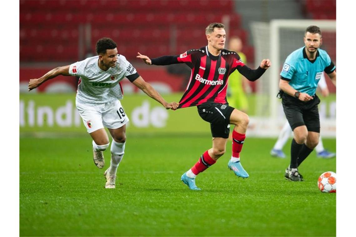 Augsburgs Ricardo Pepi (l) unterzieht das Trikot von Leverkusens Florian Wirtz einem Belastungstest. Foto: Marius Becker/dpa