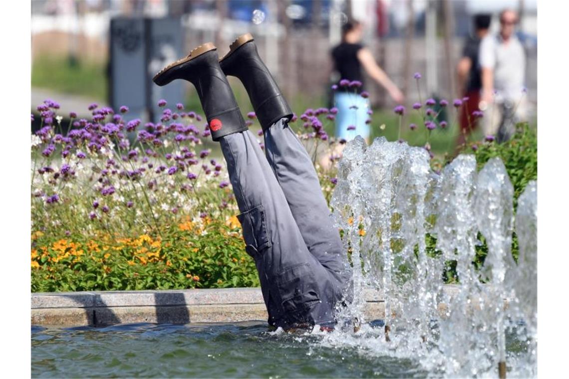 Aus einem Brunnen in der Innenstadt ragen zwei Beine mit Gummistiefeln einer Installation hervor. Foto: Uli Deck