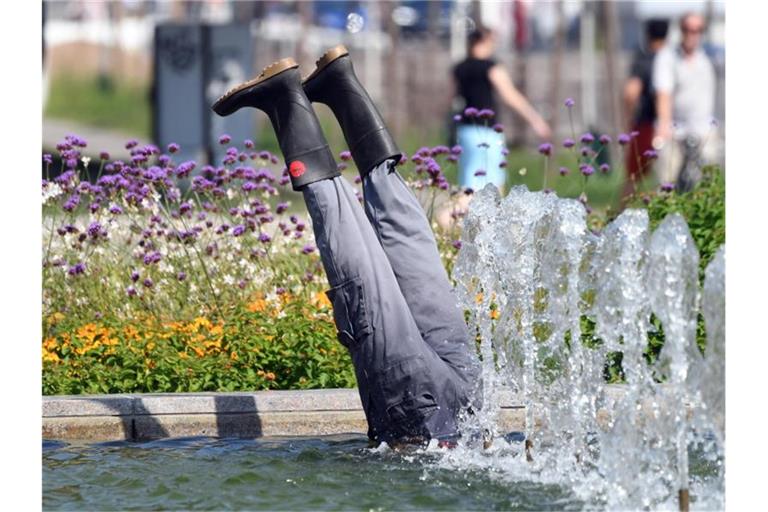 Aus einem Brunnen ragen zwei Beine mit Gummistiefeln hervor. Foto: Uli Deck