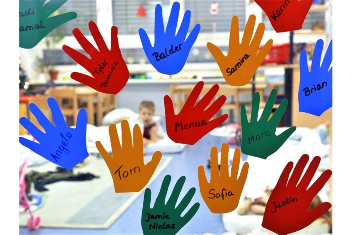 „Gute-Kita“-Gesetz - Trotz Milliarden hagelt es Kritik Aus Folien geschnittene Kinderhände hängen mit den jeweiligen Namen an der Eingangstür einer Kindergruppe in einer Tagesstätte. Foto: Rainer Jensen/dpa