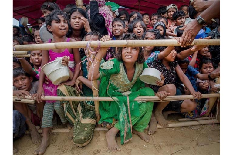 Aus Myanmar vertriebene Kinder der Rohingya warten in einem Flüchtlingslager in Bangladesch auf Nahrungsmittel. Foto: Dar Yasin/AP/dpa