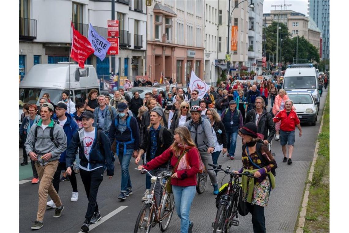 Demos gegen Corona-Politik in Berlin - Polizei-Großeinsatz Aus Protest gegen die Corona-Politik wandern Demonstranten durch eine Straße. Neun Demonstrationen waren von der Polizei verboten worden. Foto: Christophe Gateau/dpa