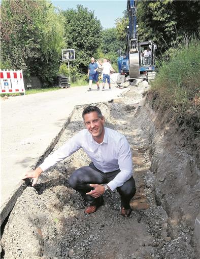 Ausbau der K1900 in Käsbach: Straßenbauamtschef Stefan Hein zeigt, dass Trag- und Deckschichten nur zwölf Zentimeter stark sind. Nach der Sanierung werden es etwa 22 Zentimeter sein. Der Graben am Fahrbahnrand ist vorbereitet, um Entwässerungsrohre aufzunehmen. Foto: A. Fechter