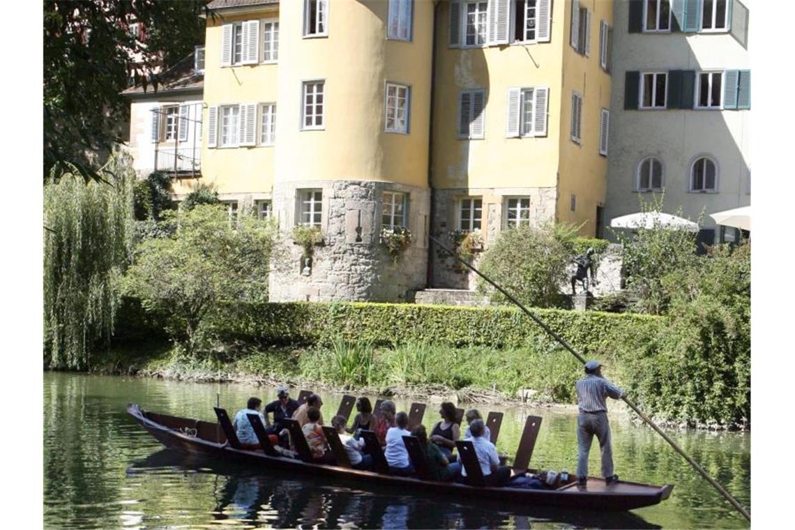 Ausflügler bei einer Stocherkahnfahrt vor dem Hölderlinturm in Tübingen. Foto: Bernd Weissbrod/dpa/Archivbild