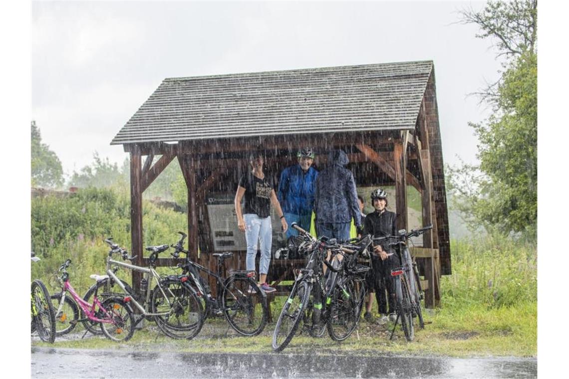 Ausflügler haben sich bei starkem Regen im Erzgebirge untergestellt. Foto: Bernd März/dpa-zentralbild/dpa