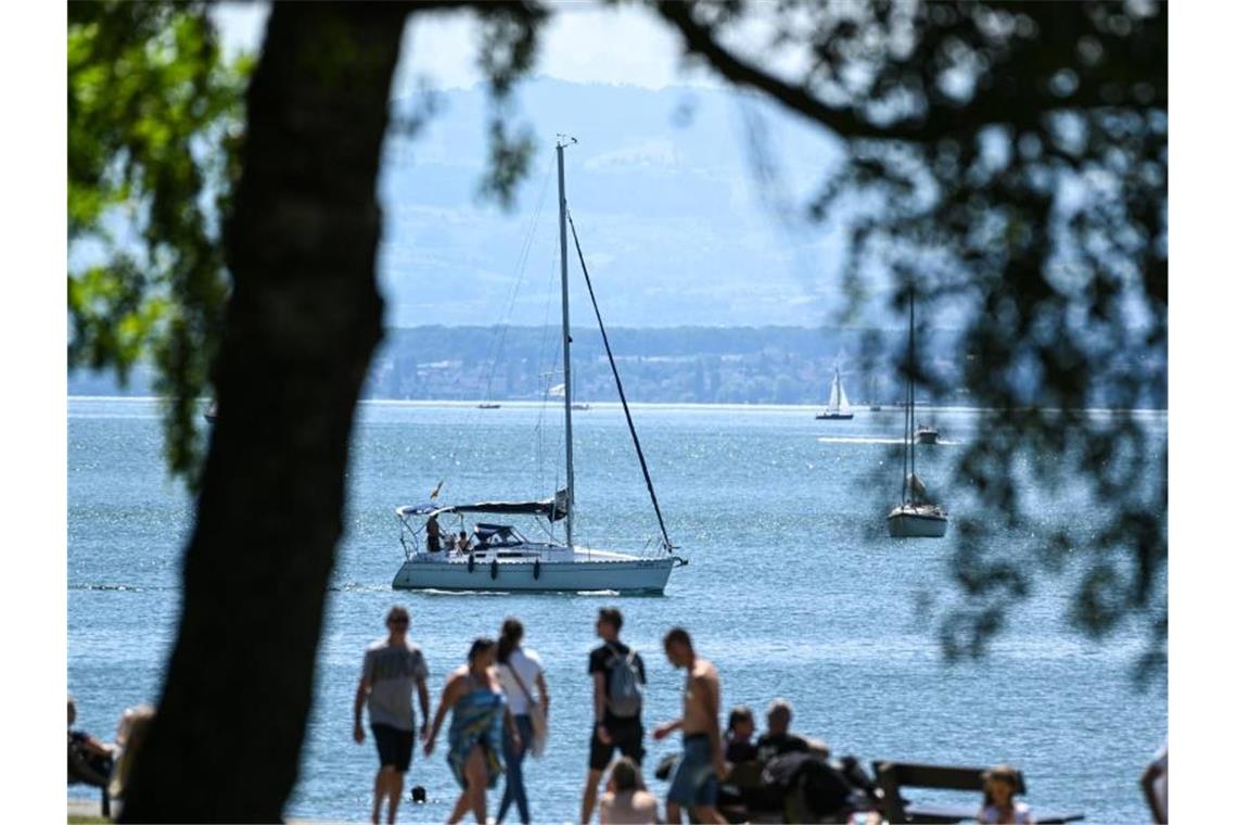 Ausflügler laufen am Ufer des Bodensee entlang. Foto: Felix Kästle/dpa/Archivbild