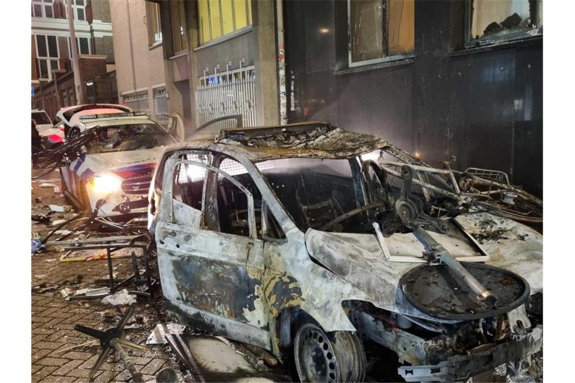 Corona-Krawalle in Nachbarstaaten breiten sich aus Ausgebrannte Autos, darunter auch Polizeifahrzeuge, stehen auf einer Straße in Rotterdam. Foto: Hollandse Hoogte/Inter Visual Studio/ANP/dpa