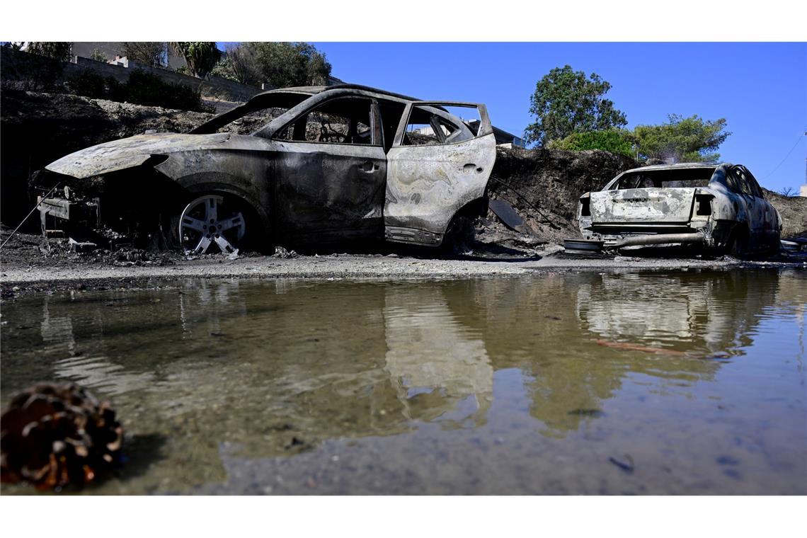 Bilder des Tages Ausgebrannte Autos spiegeln sich im Wasser nach einem Waldbrand in dem Dorf südöstlich von Athen.