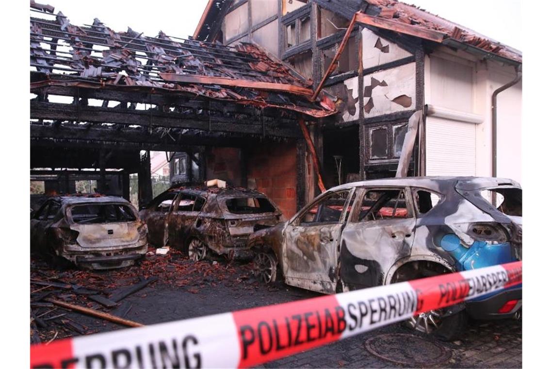 Ausgebrannte Autos stehen in einem Carport zwischen zwei Doppelhaushälften. Foto: Thomas Warnack/dpa