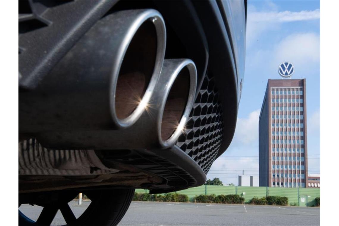 Auspuffrohre eines Volkswagen, fotografiert mit dem Markenhochhaus am VW Werk Wolfsburg. (Archivbild). Foto: Julian Stratenschulte/dpa