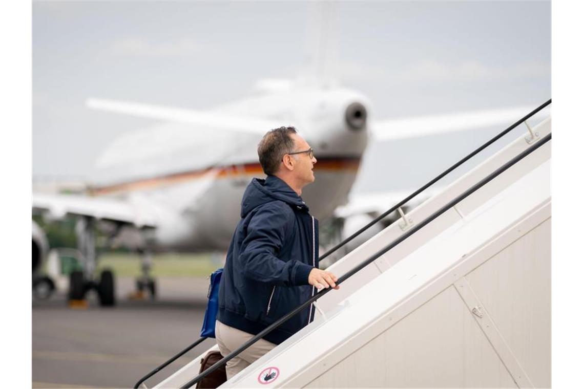 Außenminister Heiko Maas geht die Gangway zum Airbus A319 der Luftwaffe auf dem militärischen Teil des Flughafens Tegel hinauf. Im Hintergrund steht ein defekter Airbus A321 der Luftwaffe, der eigentlich für die Reise vorgesehen war. Foto: Kay Nietfeld