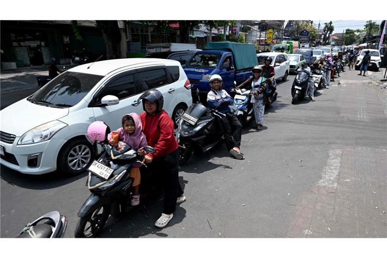Auto- und Motorradfahrer auf Bali stehen Schlange für Sprit.