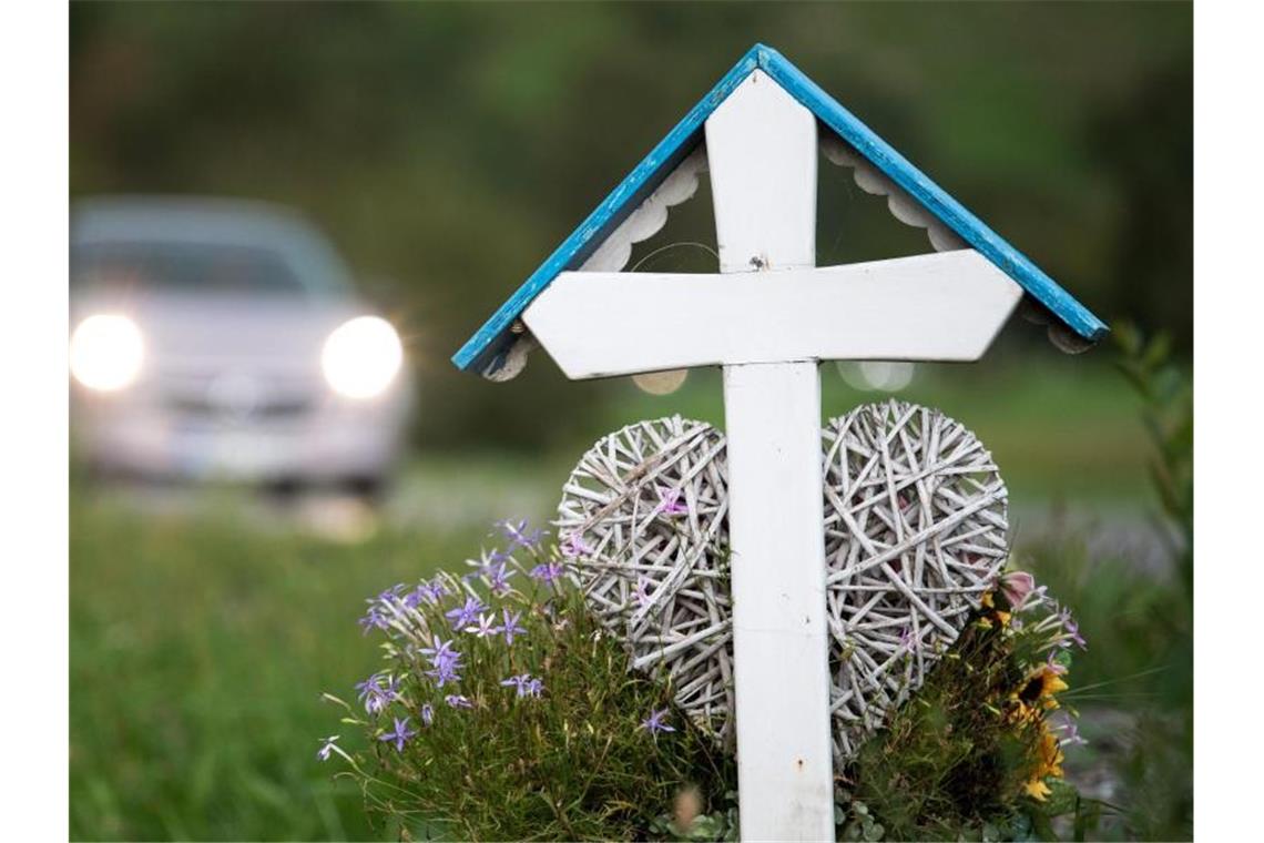 Autos fahren an einem weißen Kreuz für eine Unfalltote vorbei. Im ersten Quartal 2019 sind auf deutschen Straßen 633 Menschen gestorben. Foto: Sebastian Gollnow/Archiv