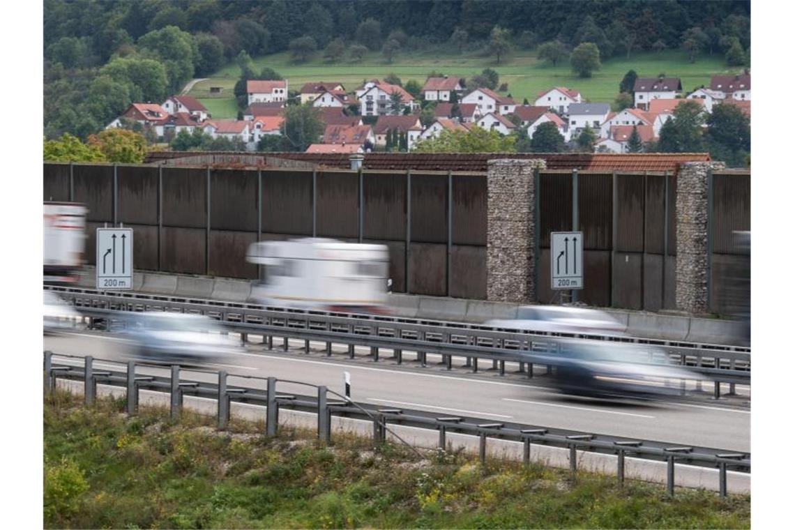 Autos fahren auf der A8 neben einer Lärmschutzwand. Im Hintergrund ist der Ort Gruibingen zu sehen. Foto: Marijan Murat/Archiv