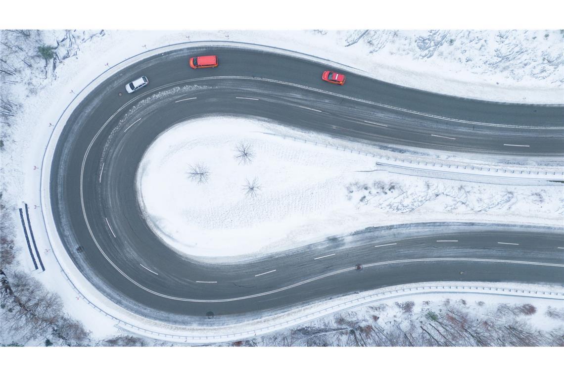 Autos fahren auf einer von Schnee geräumten Serpentine entlang. (Luftaufnahme mit einer Drohne).