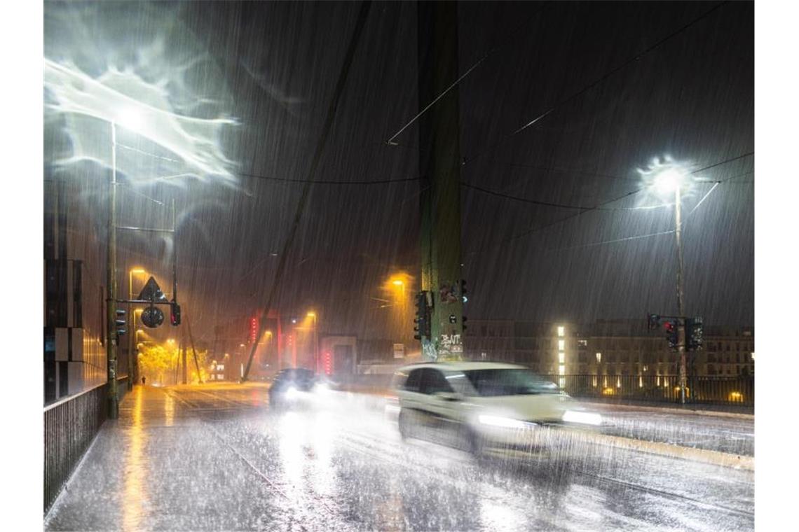 Autos fahren bei Starkregen und Gewitter durch Düsseldorf. Foto: Marcel Kusch/dpa