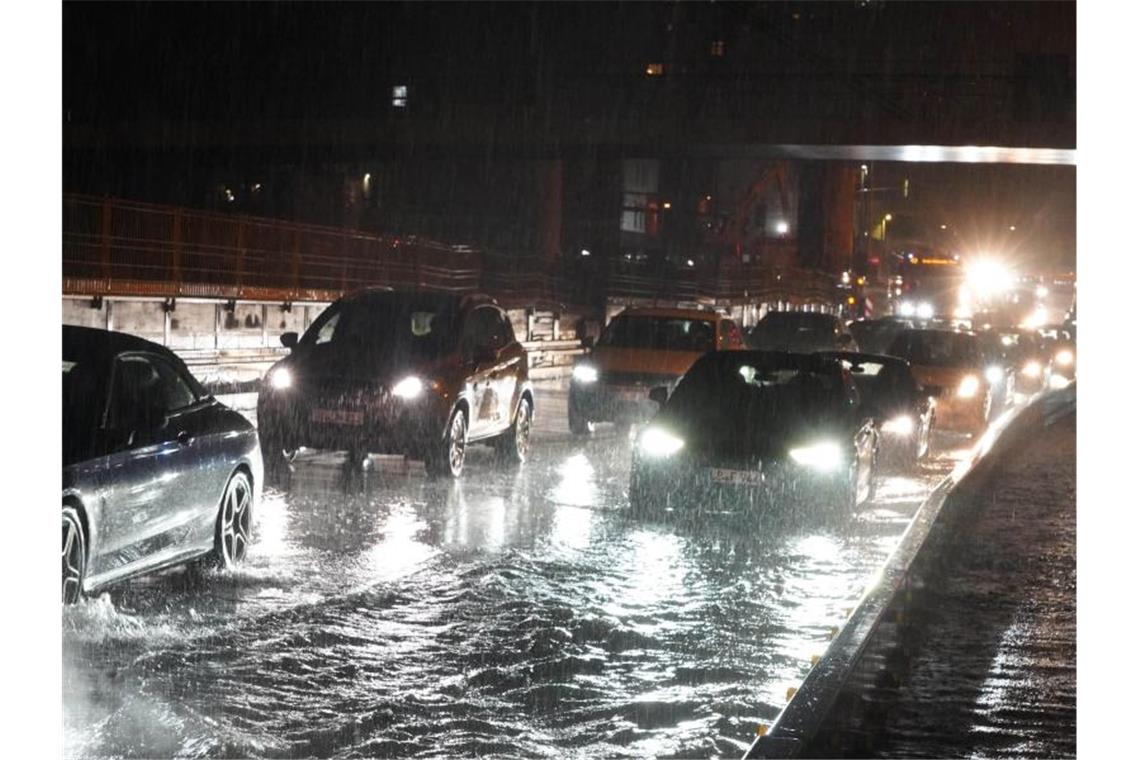 Autos fahren über die überflutete Schillerstrasse am Stuttgarter Hauptbahnhof. Foto: Andreas Rosar/dpa