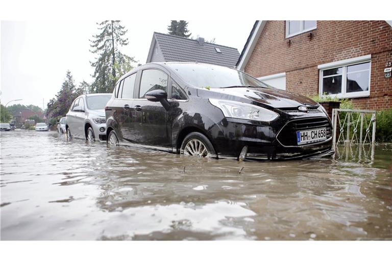 Autos stehen auf einer Überfluteten Straße in Hamburg-Bergedorf. Starkregen hielt die Feuerwehr in Hamburg und Schleswig-Holstein in Atem.