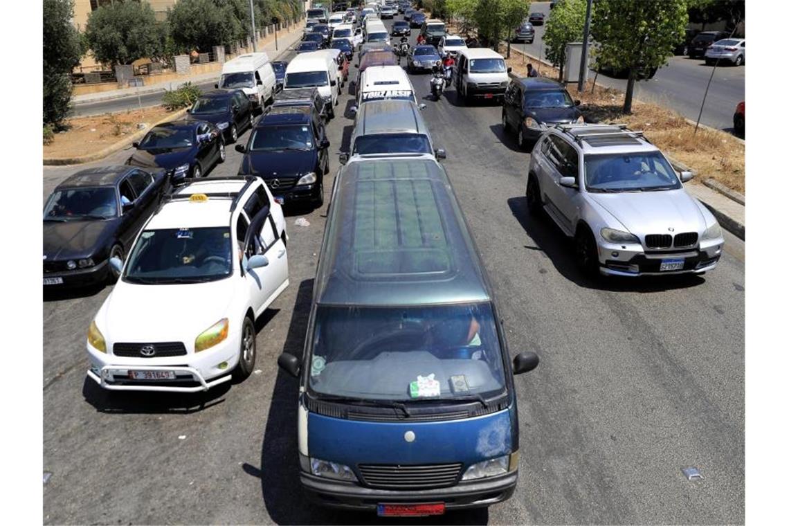 Autos und Kleinbusse stehen vor einer Tankstelle in Beirut in einer Schlange. Foto: Hussein Malla/AP/dpa