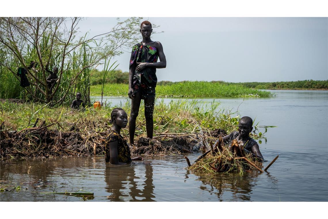 Ayen Deng Duot (r) und ihre Familie befestigen ihre Insel mit Pflanzen und Schlamm aus dem Sumpf, um zu verhindern, dass ihr Haus am Nil überflutet wird.