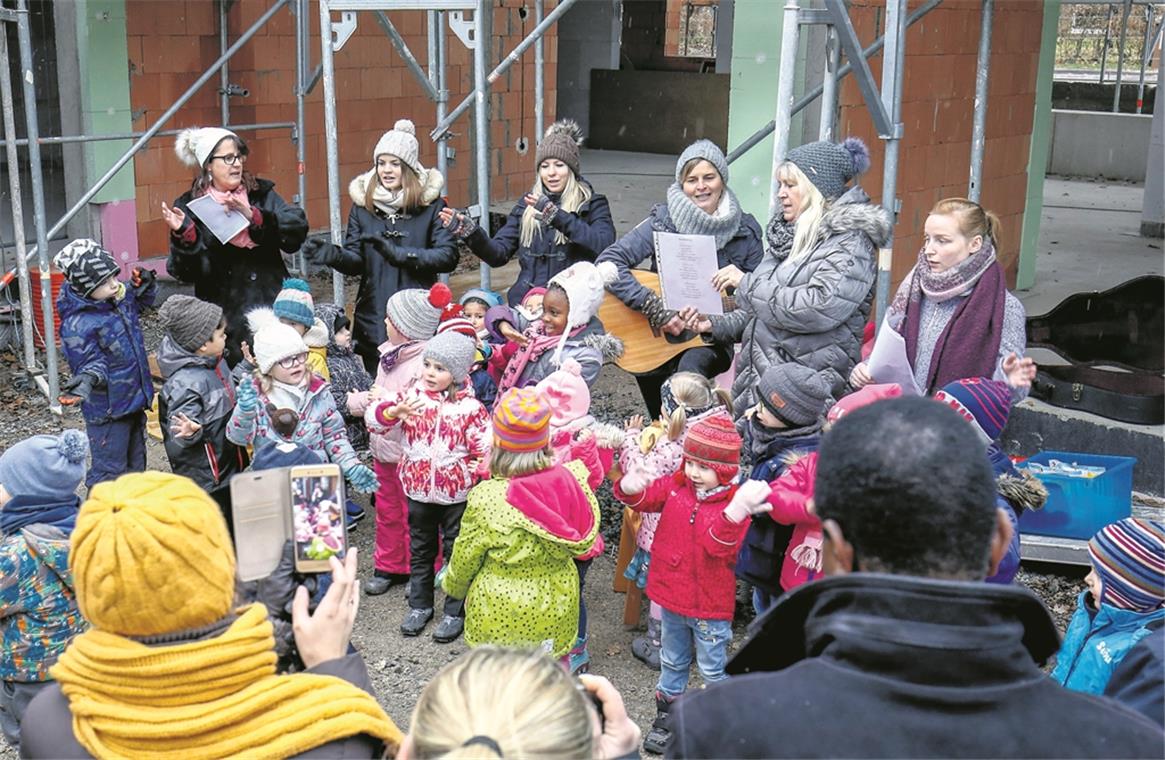 BACKNANG (inf). „In meinem Garten groß und schön, da soll nun bald mein Kindi stehn.“ So sangen die Kindergartenkinder gestern beim Richtfest am evangelischen Kindergarten Sachsenweiler. Der Neubau, der zurzeit nach den Plänen der Backnanger Architekten Sibylle und Tilman Nussbaum an der Stelle des abgebrochenen Kindergartens entsteht, kostet ungefähr 2,2 Millionen Euro und soll im Sommer nächsten Jahres fertig werden. Der Neubau bietet Platz, um eine dritte Gruppe zu eröffnen. Dekan Wilfried Braun und Pfarrerin Ulrike Heinrich verliehen dem Richtfest einen geistlichen Charakter. So hielt die Pfarrerin eine Andacht und begleitete den Richtspruch der Zimmerleute mit einem Gebet, und der Dekan stellte schon in der Begrüßung den kirchlichen Bezug her. Während der Bauzeit, die mit den Abbrucharbeiten im April begonnen hat, ist der Kindergarten mit seinen beiden Gruppen – den Bienen und den Schmetterlingen – in mehreren benachbarten Gebäuden untergekommen: in der Schule, bei der Mennonitengemeinde und in der evangelischen Kirche. Von dort aus verfolgen die Kinder, wie Kita-Leiterin Jutta Hofer erzählt, mit großem Interesse das Entstehen ihrer künftigen Bleibe und schauen auch öfter direkt dort vorbei. Foto: A. Becher