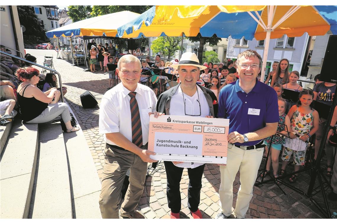 BACKNANG (sas). Bei herrlichem Sommerwetter feierte die Jugendmusik- und -kunstschule Backnang am Samstag ihr Sommerfest im Markgrafenhof. Unter blau-gelben Schirmen suchten die Besucher Plätze im Schatten, um dem musikalischen Programm zu folgen. Daneben gab es nicht nur viele Mitmachangebote, sondern vor allen Dingen auch die finanzielle Unterstützung der Kreissparkasse. Thomas Hofmann, stellvertretendes Vorstandsmitglied der Kreissparkasse, überreichte dem Schulleiter der Musikschule, Michel Unger, und dem Ersten Bürgermeister Siegfried Janocha einen Scheck über 15000 Euro. „Die Kreissparkasse ist für uns ein treuer und wertvoller Partner, der seit über 20 Jahren immer ein offenes Ohr hat“, lobte Unger die Zusammenarbeit. Die Sparkasse unterstützt jährlich die Musikschulen im Kreis mit einer Spende. Hofmann dazu: „Uns ist es wichtig, in musikalische Bildung und somit in unsere Zukunft zu investieren.“ Auch Janocha bedankte sich im Namen der Stadt: „Es ist unterstützenswert, die Kinder an das Musizieren heranzuführen. Und es ist ein Betrag, den wir dringend gebrauchen können.“ Foto: A. Becher