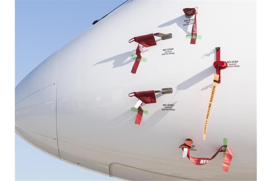 Bänder mit der Aufschrift „Remove Before Flight“ (dt. Vor dem Flug entfernen) sind an einem Flugzeug der Schweizer Fluggesellschaft Swiss befestigt. Foto: Ennio Leanza/KEYSTONE/dpa
