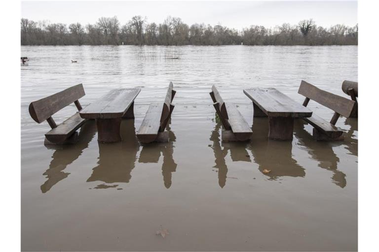 Bänke und Tische stehen auf einem Campingplatz bereits im Hochwasser. Foto: Boris Roessler/dpa/Archivbild