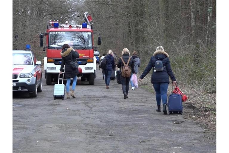 Bahnreisende ziehen ihre Rollkoffer über eine Straße bei Rheine. 200 Reisende mussten wegen einer gesperrten Bahnstrecke in Busse umsteigen. Foto: -/Nord-West-Media TV/dpa