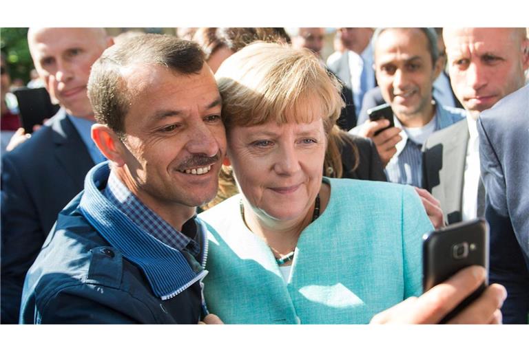 Bald zehn Jahre her: Angela Merkel (CDU) lässt sich nach dem Besuch einer Erstaufnahmeeinrichtung für Asylbewerber in Berlin-Spandau für ein Selfie zusammen mit einem Flüchtling fotografieren. (Archivbild)