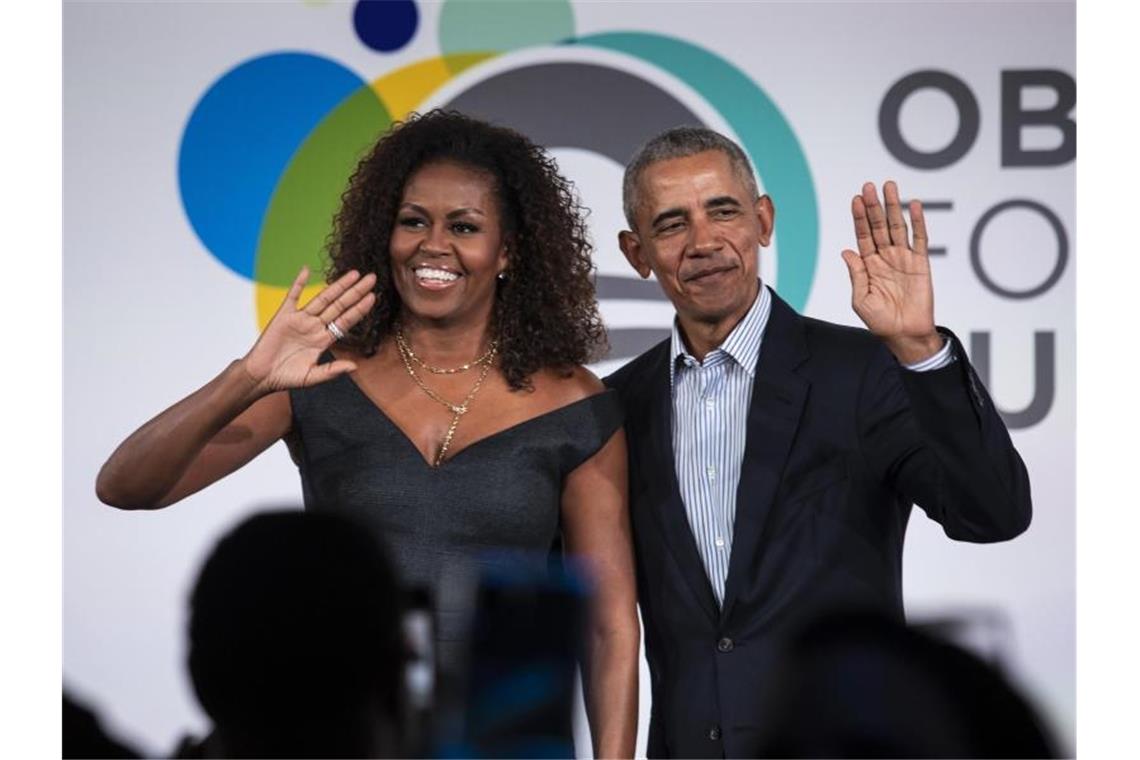 Barack und Michelle Obama winken in die Kameras. Foto: Ashlee Rezin Garcia/Chicago Sun-Times/AP/dpa/Archivbild