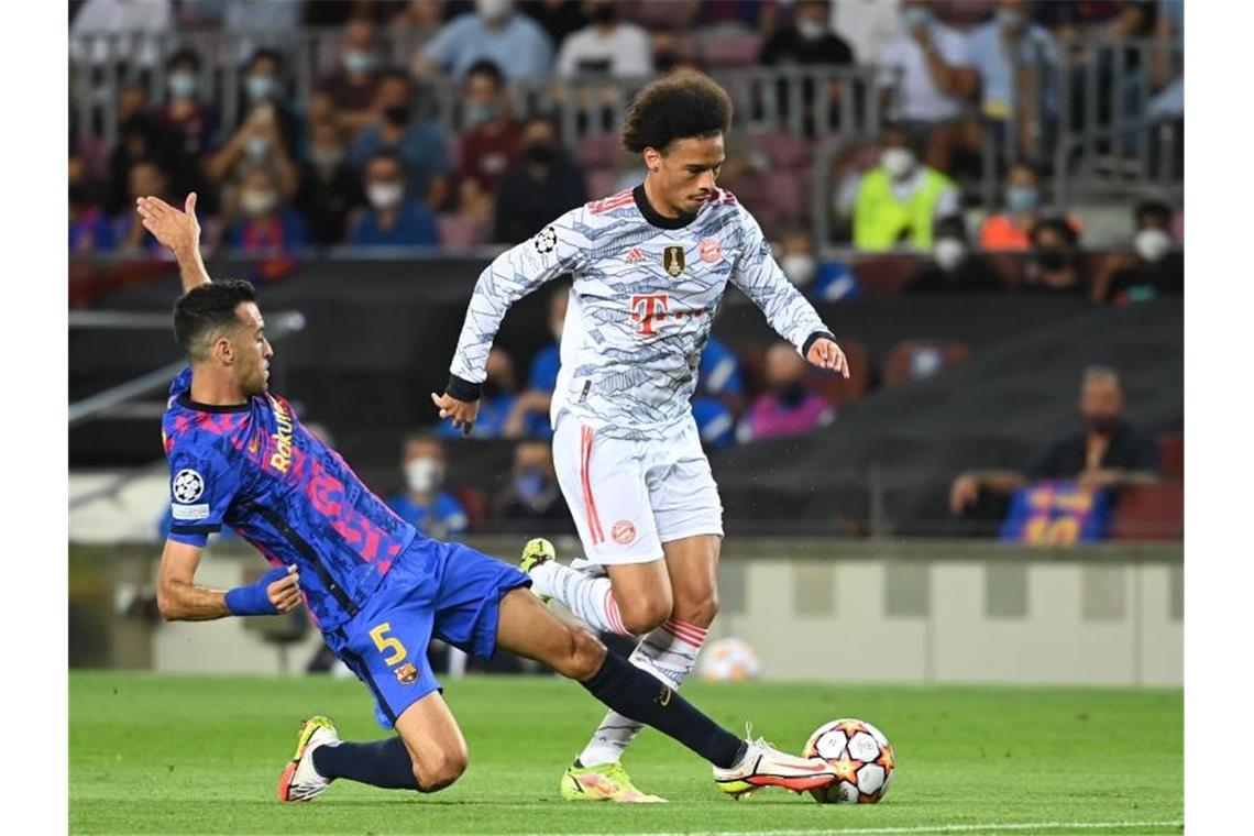 Barcelonas Mittelfeldspieler Sergio Busquets (l) rettet gegen Leroy Sané. Foto: Sven Hoppe/dpa