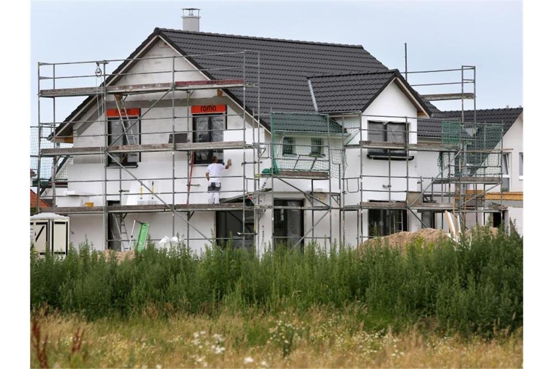 Bauarbeiter arbeiten an der Fertigstellung von Einfamilienhäusern. Foto: Bernd Wüstneck/Archivbild