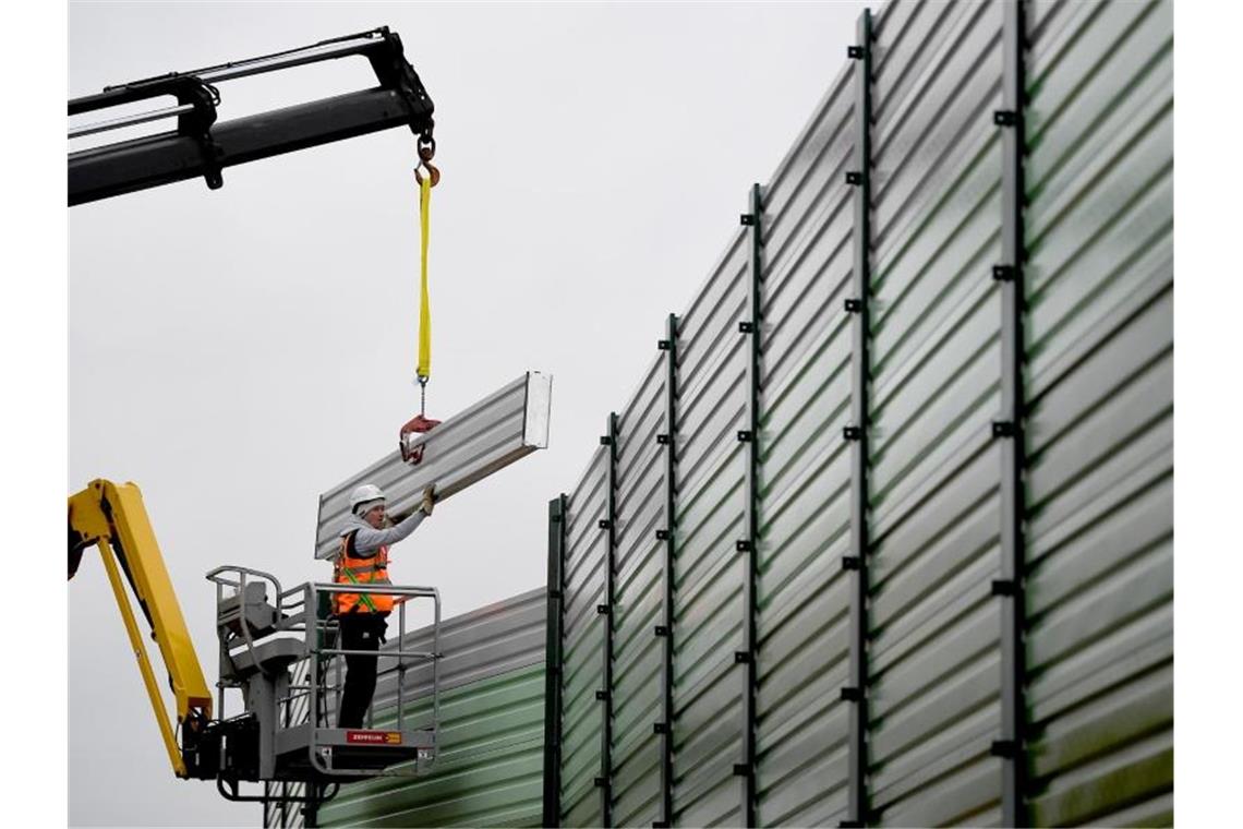 Bauarbeiter errichten einen Lärmschutz. Foto: Britta Pedersen/dpa-Zentralbild/dpa