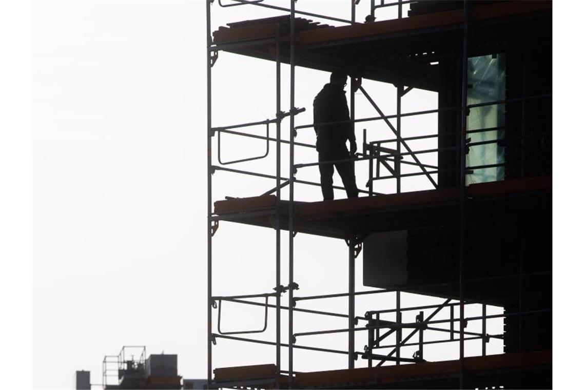 Bauarbeiter stehen auf einem Gerüst. Foto: Julian Stratenschulte/dpa/Archivbild