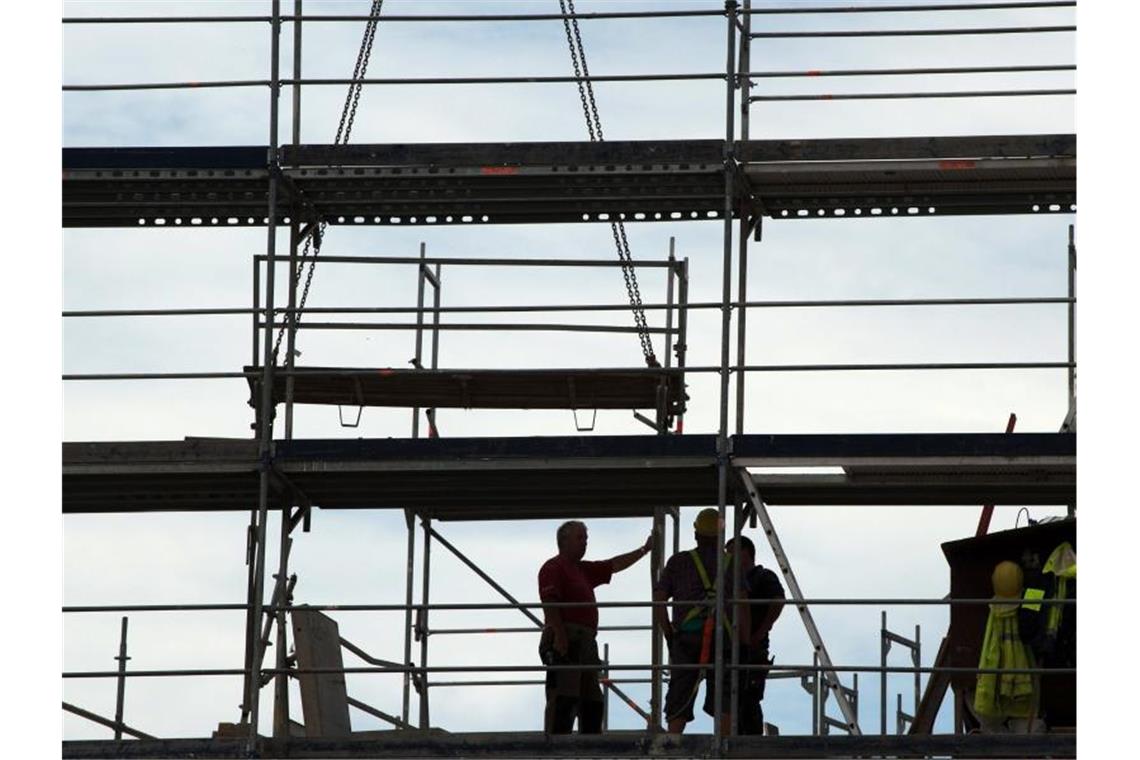 Institut: Beschäftigte ohne Tarifvertrag arbeiten länger Bauarbeiter zeichnen sich auf einem Gerüst als Silhouette ab. Foto: Sebastian Kahnert/dpa-Zentralbild/dpa