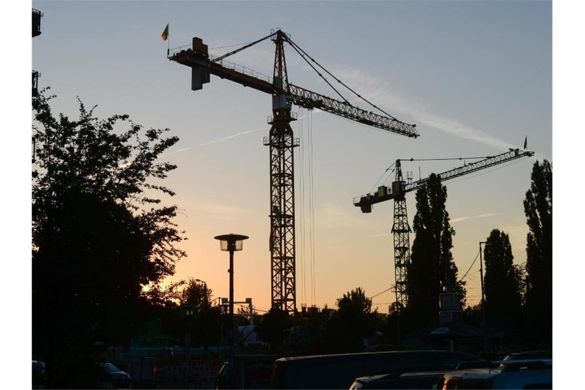 Baukräne am Abend in der Dämmerung bei untergehender Sonne. Foto: Jens Kalaene/ZB/dpa/Archivbild