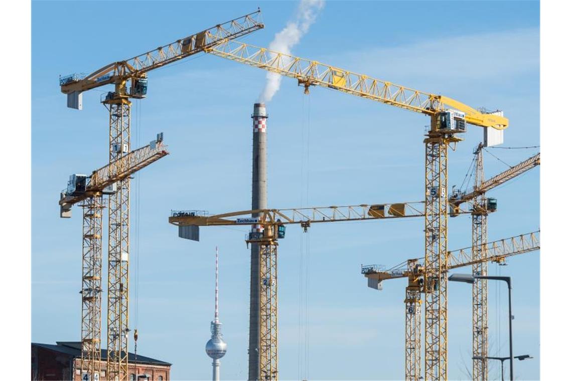 Baukräne stehen auf einer Baustelle. Foto: Christophe Gateau/Archivbild