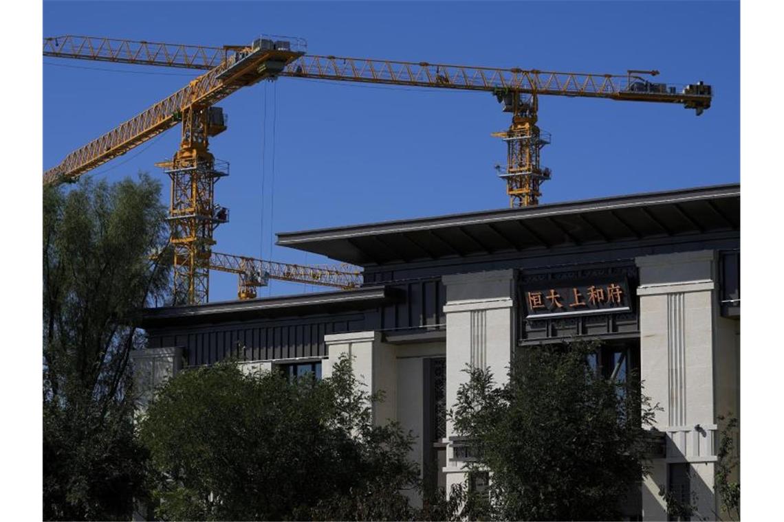 Baukräne stehen in der Nähe eines Bürogebäudes des Evergrande New Housing Development Showroom. Foto: Andy Wong/AP/dpa