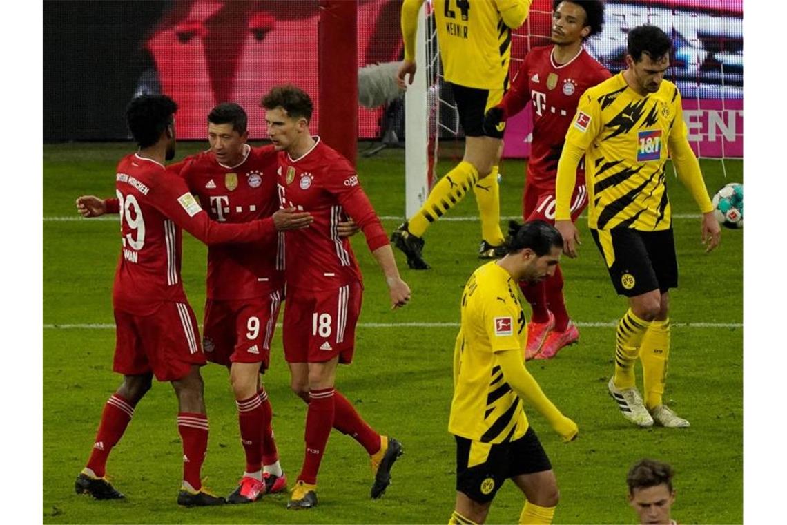 Bayern besiegt BVB - RB bleibt dran - Später Hertha-Sieg Bayern-Stürmer Robert Lewandowski (M) jubelt mit den Mannschaftskameraden Kingsley Coman (l) und Leon Goretzka über seinen Treffer zum zwischenzeitlichen 2:2. Foto: Günther Schiffmann/AFP-POOL/dpa