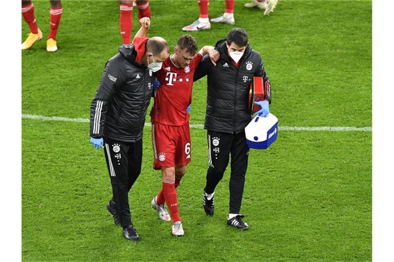 Bayerns Joshua Kimmich geht nach einer ärztlichen Behandlung gestützt von den Betreuern vom Platz. Foto: Martin Meissner/Pool AP/dpa