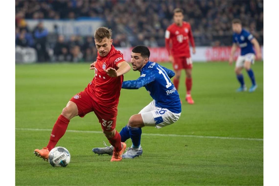 Bayerns Matchwinner Joshua Kimmich (l) setzt sich gegen Schalkes Nassim Boujellab durch. Foto: Bernd Thissen/dpa
