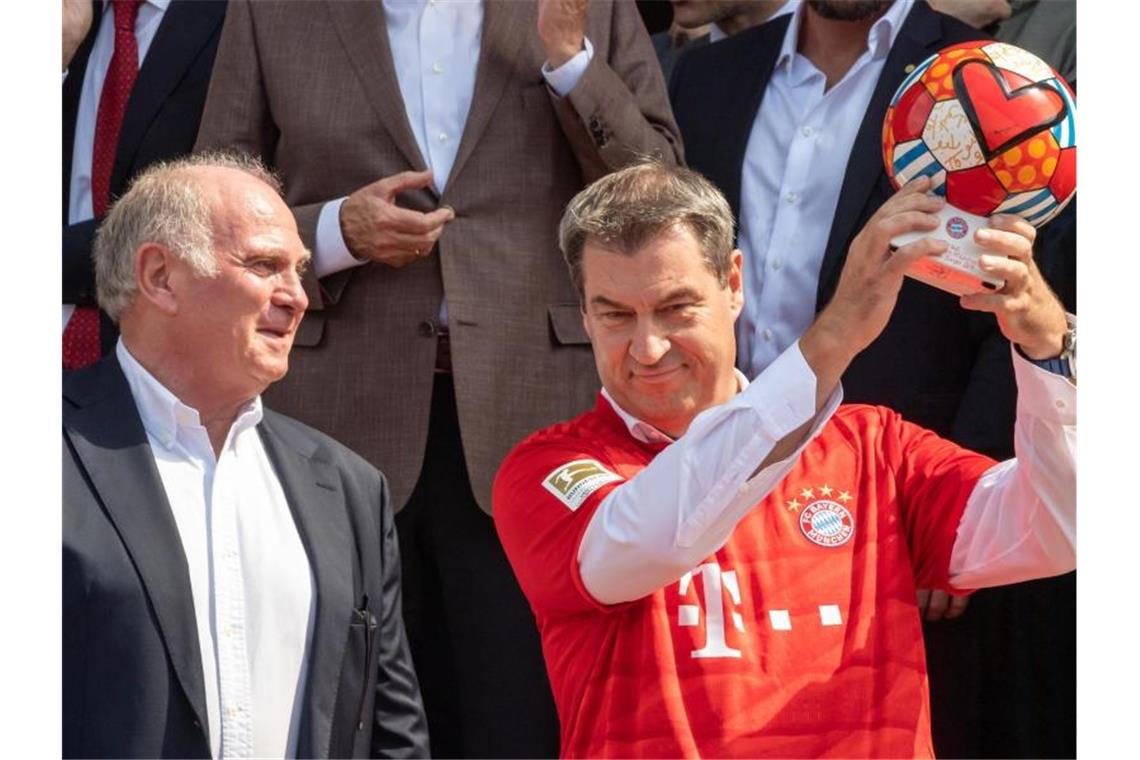 Bayerns Ministerpräsident Markus Söder (r) im FCB-Trikot und Vereinspräsident Uli Hoeneß posieren nach der Ehrung des FC Bayern München. Foto: Peter Kneffel