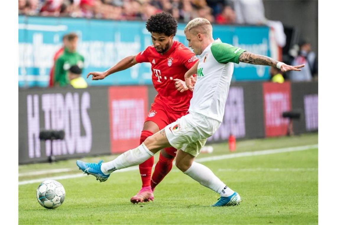 Bayerns Serge Gnabry (l) hat es gegen Augsburgs Philipp Max schwer. Foto: Matthias Balk/dpa