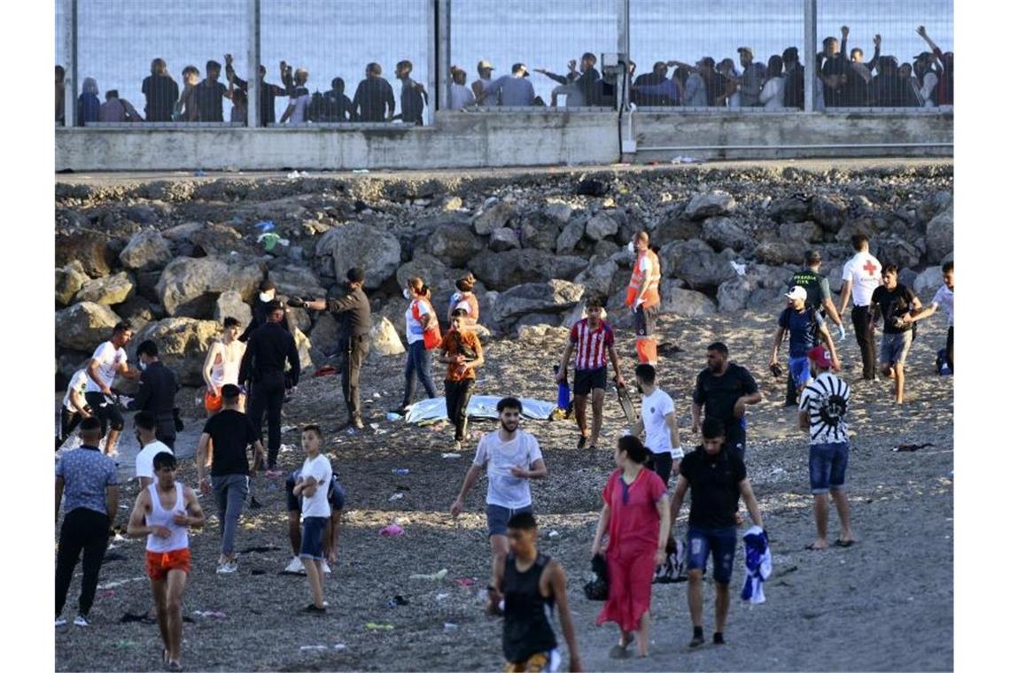 Marokko setzt Spanien mit Migranten in Ceuta unter Druck Beamte der Guardia Civil und Mitglieder des Roten Kreuzes beobachten Menschen aus Marokko, die die Grenze überquert haben. Foto: Antonio Sempere/Europa Press/dpa