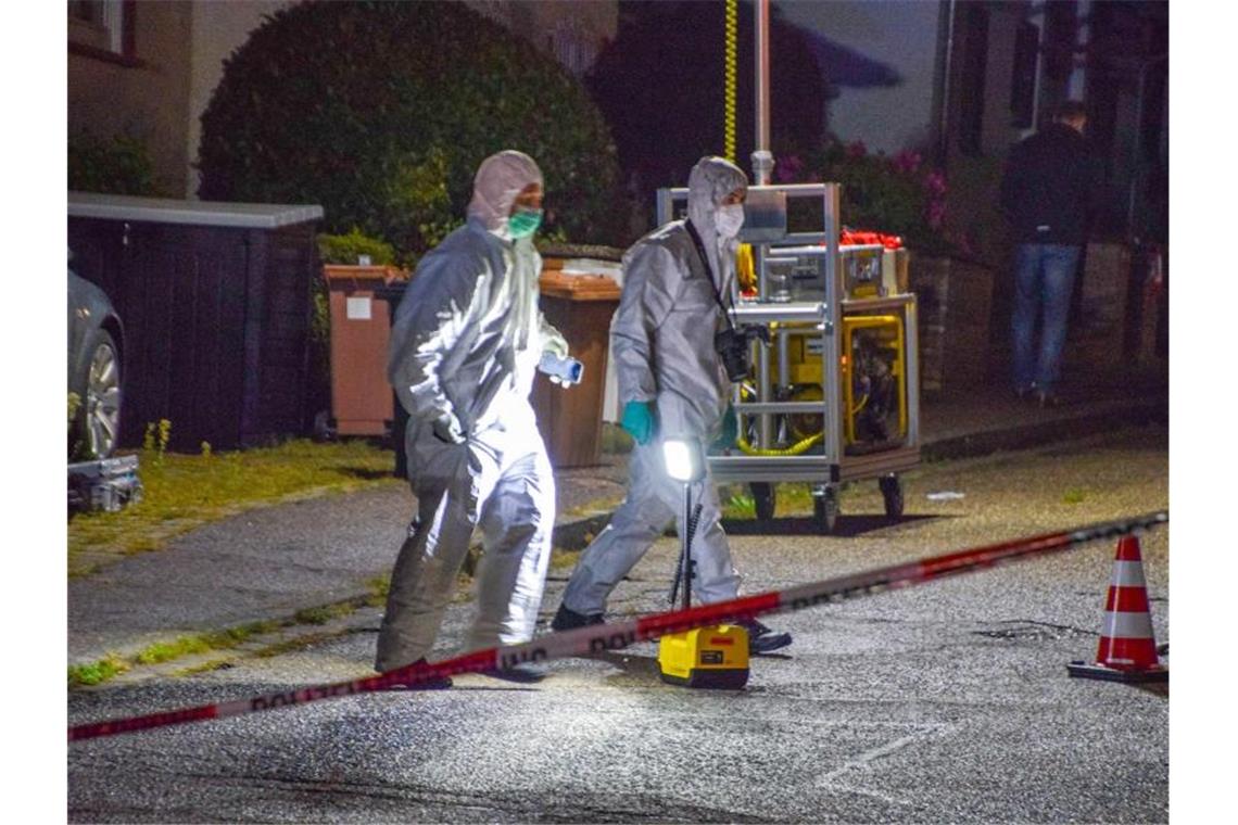 Beamte der Spurensicherung gehen in ihren Overalls über eine Straße. Foto: Julian Buchner/dpa