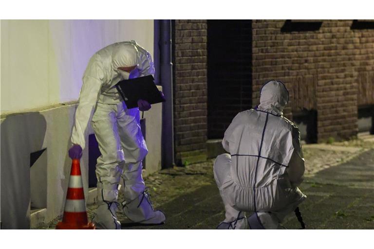 Beamte der Spurensicherung in Spurensicherungsanzügen begutachten den Tatort.
